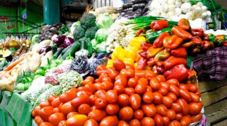 Tomates y verduras frescas en puesto de mercado local, lleno de color y variedad.