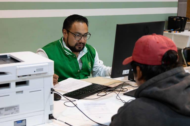 Oficial revisando documentos con una persona en una oficina.