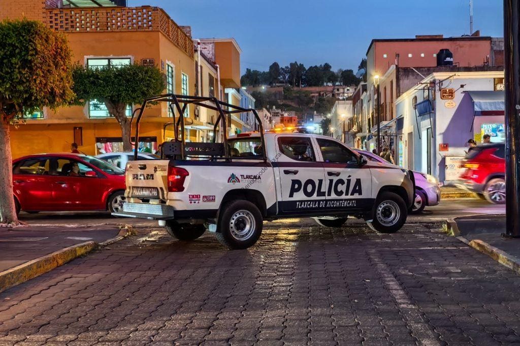 Policía de Tlaxcala en una calle del centro histórico, patrullando durante el anochecer en Tlaxcala, México, mostrando presencia policial en una zona urbana con comercio y flujo peatonal.