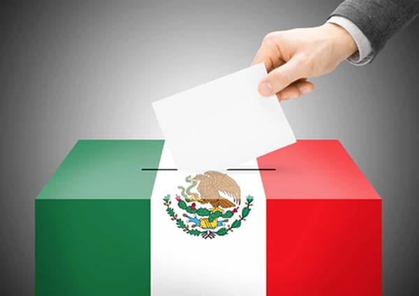 Elección en México con una urna decorada con la bandera del país y un mano colocando un voto.