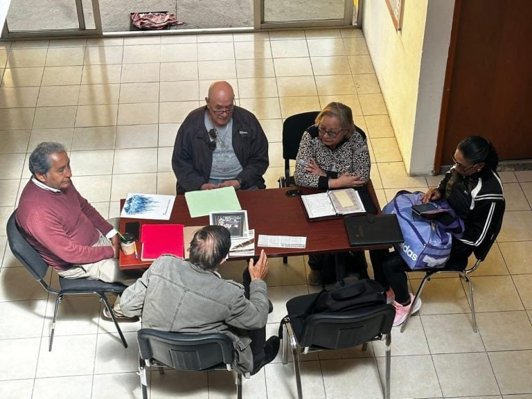 Redacción y periodistas en una mesa de reunión, discutiendo documentos y notas importantes en un espacio interior.
