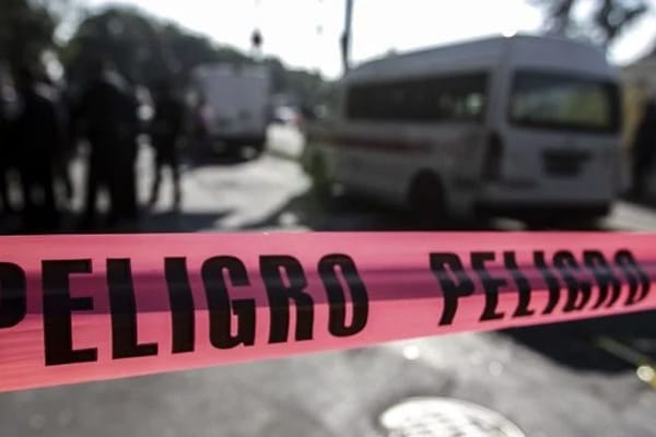 Peligro, línea de peligro de color rosa marca la zona de un incidente con presencia policial y vehículos en fondo de una calle urbana.