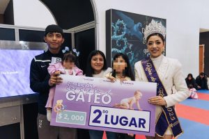 Premio a la segunda lugar en el concurso de gateo en Tlaxcala, entregado por autoridades locales durante evento infantil en un lugar cerrado con niños y adultos.