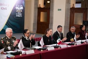 1. Autoridades civiles y militares en una mesa de honor durante el evento en Tlaxcala, con banderas y un cartel que dice "2025 Año de La Mujer Indígena".