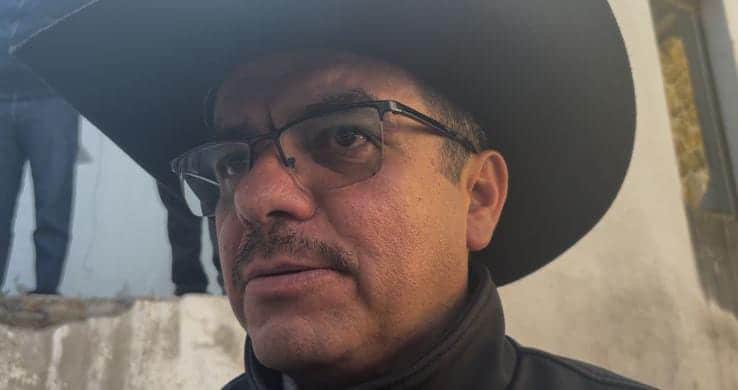 1. Hombre con gafas y sombrero de ala ancha mirando pensativo, fondo urbano, luz natural.