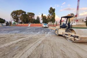 1. Maquinaria de construcción trabajando en una obra vial en Tlaxcala, México, con árboles y cielo despejado en el fondo.