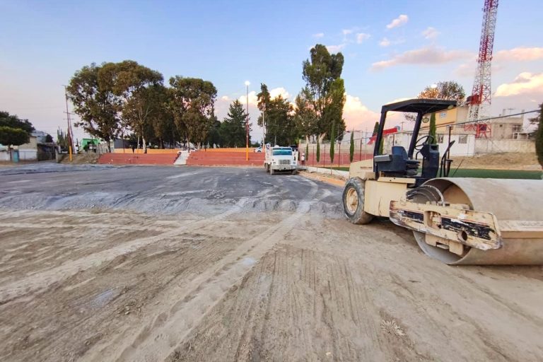 1. Maquinaria de construcción trabajando en una obra vial en Tlaxcala, México, con árboles y cielo despejado en el fondo.