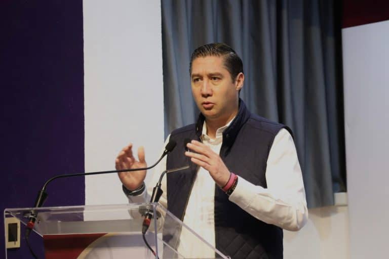Crítico político en conferencia, expresando ideas durante un evento público.