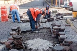 1. Obreros trabajando en la reparación y pavimentación de calles en Tlaxcala, México, con herramientas y materiales de construcción.