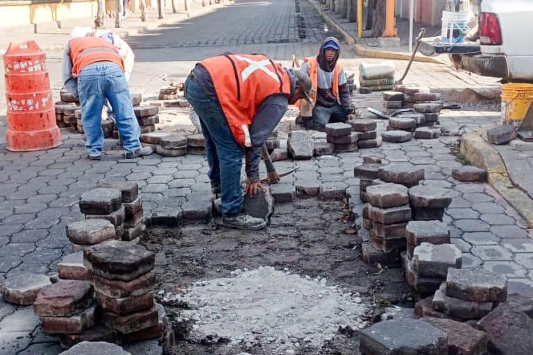 1. Obreros trabajando en la reparación y pavimentación de calles en Tlaxcala, México, con herramientas y materiales de construcción.