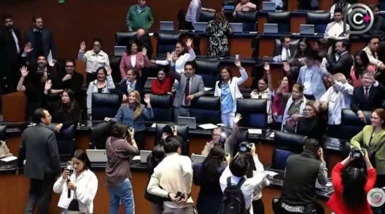 Diputados en la LXIV Legislatura de México en sesión plenaria, algunos levantando la mano, otros tomando fotos y conversando en el recinto parlamentario.