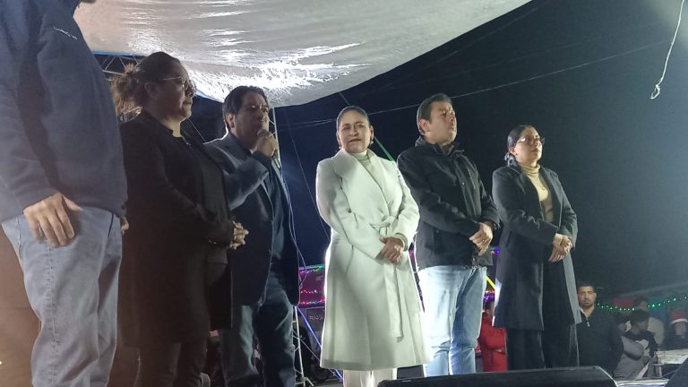 1. Personas en un evento público al aire libre, algunos con expresiones serias, vestimenta formal y casual, en un escenario con decoraciones y luces.