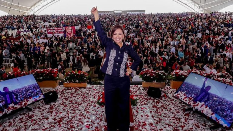 1. Ilustración de una mujer celebrando en un gran evento con multitud de personas en un estadio cubierto, rodeada de pantallas y confeti en el suelo, símbolo de éxito y liderazgo.