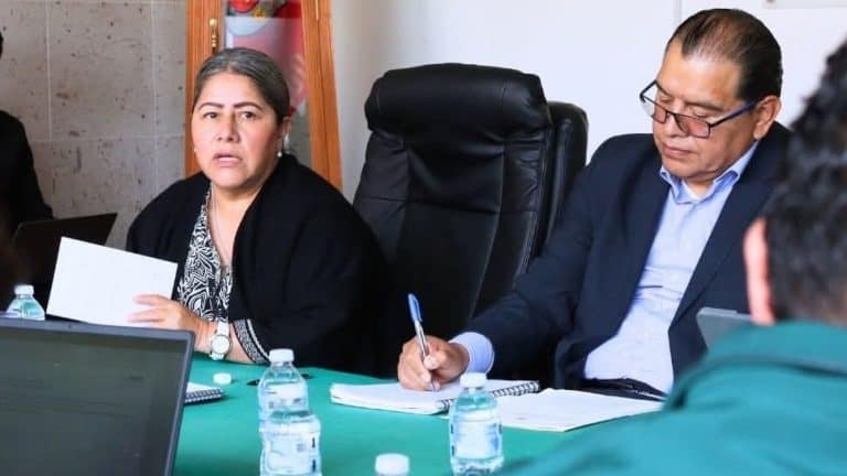 1. Mujeres y hombres en reunión formal, tomando notas y discutiendo en un entorno de oficina con botellas de agua y laptops presentes.