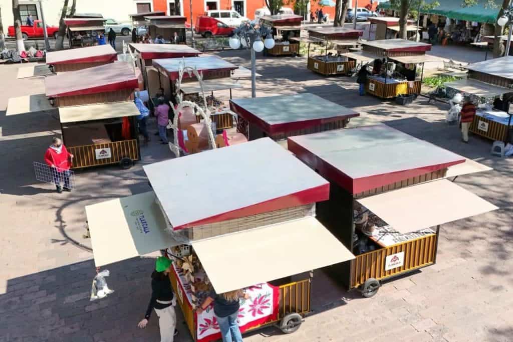 1. Puestos de venta en un mercado al aire libre en Tlaxcala, exhibiendo diferentes productos y comerciantes ofreciendo sus artículos en un día soleado.