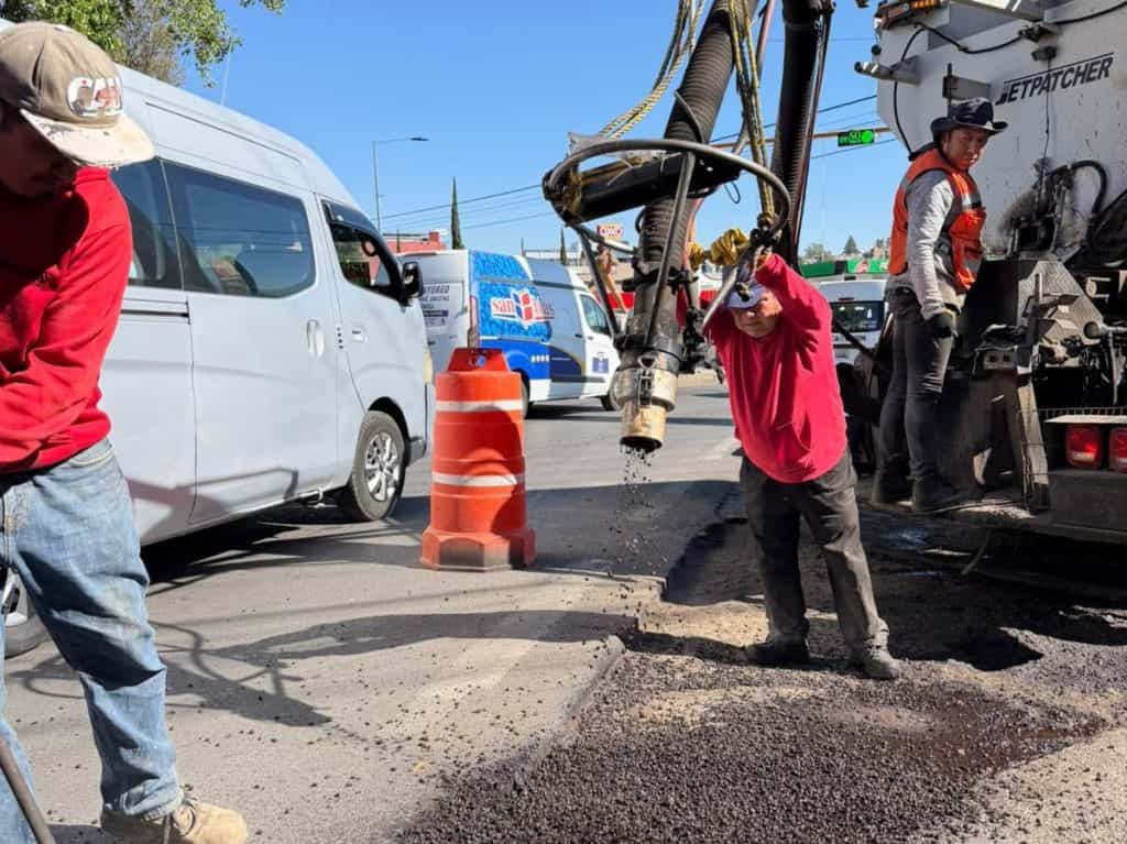 1. Trabajadores reparando una fuga de agua en una calle de Tlaxcala, en medio del tránsito vehicular, con maquinaria y señalización temporal.