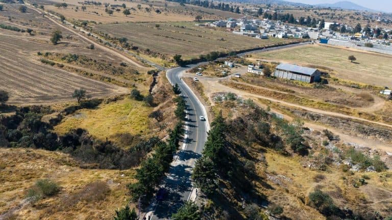 1. Carreteras rurales en Tlaxcala con paisaje agrícola y urbanización en el horizonte.