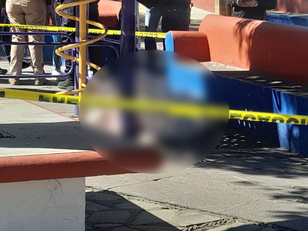 Muerto en escena de agresión con arma blanca en Tlaxcala, personan en la calle rodeada de policías y cinta de precaución, posible causa de la muerte un ataque violento, investigación en curso.
