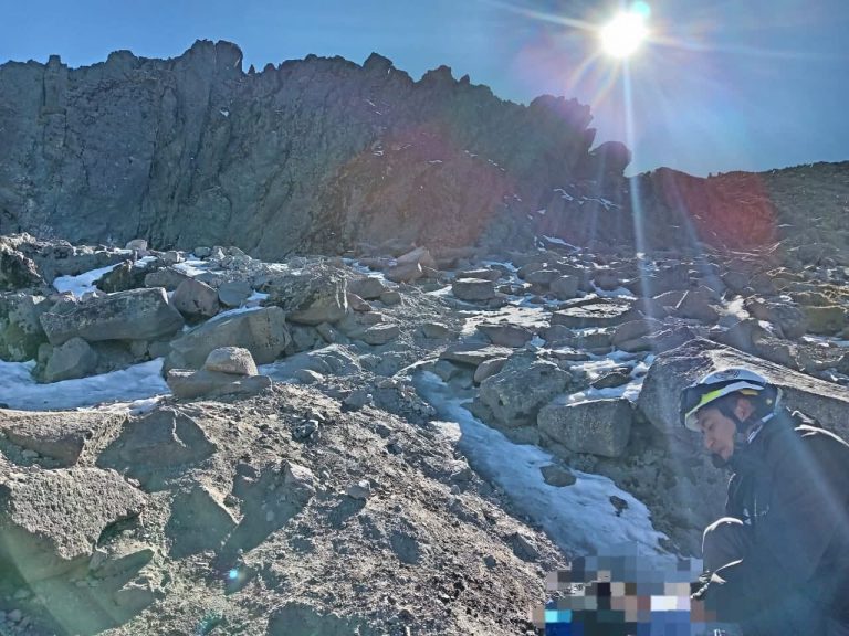 1. Joven montañista en la cima con casco, en un paisaje rocoso y soleado en las montañas heladas de Tlaxcala, México.