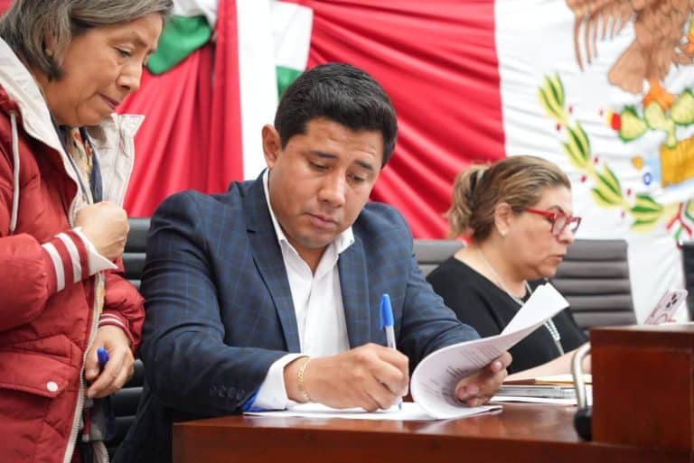 1. Persona revisando documentos en una reunión formal con fondo de bandera mexicana.