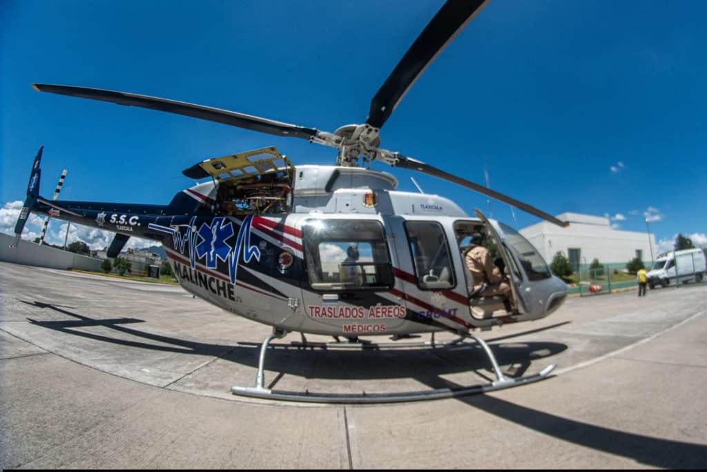 Rosen en helicóptero de emergencias en Tlaxcala, listo para transporte médico en una jornada soleada con cielo despejado. Equipamiento y pilotos preparados para atender emergencias médicas.