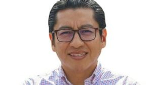 1. Hombre con gafas, sonrisa y camisa a cuadros, imagen de perfil cercano, en un fondo blanco, representando a un periodista o figura pública mexicana.