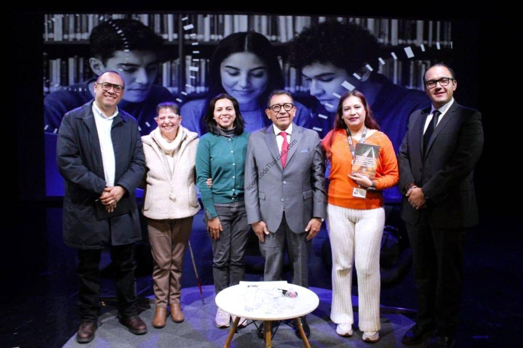 Grupo de seis personas en un evento formal, con fondo de imágenes de jóvenes en un entorno académico o cultural.
