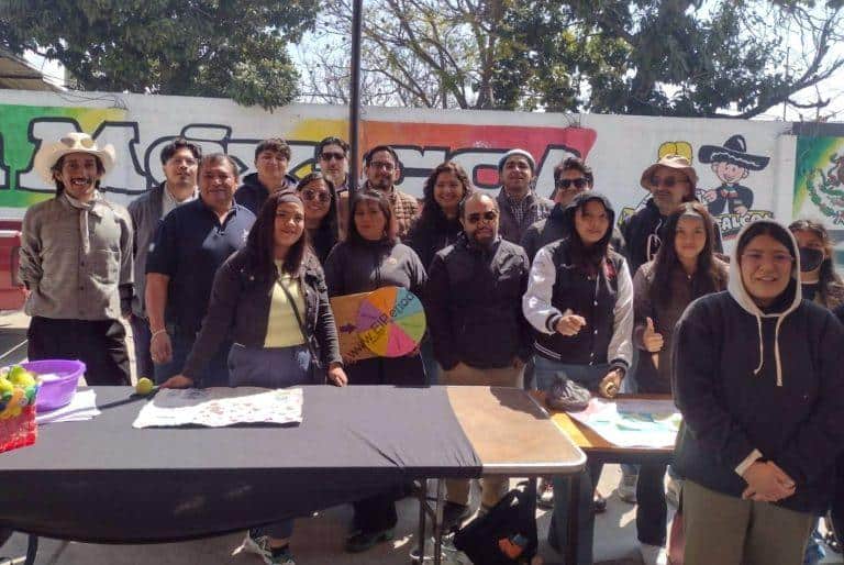 Árbol de decisiones con personas en un evento al aire libre, en un espacio con graffiti en la pared de fondo, durante el día.
