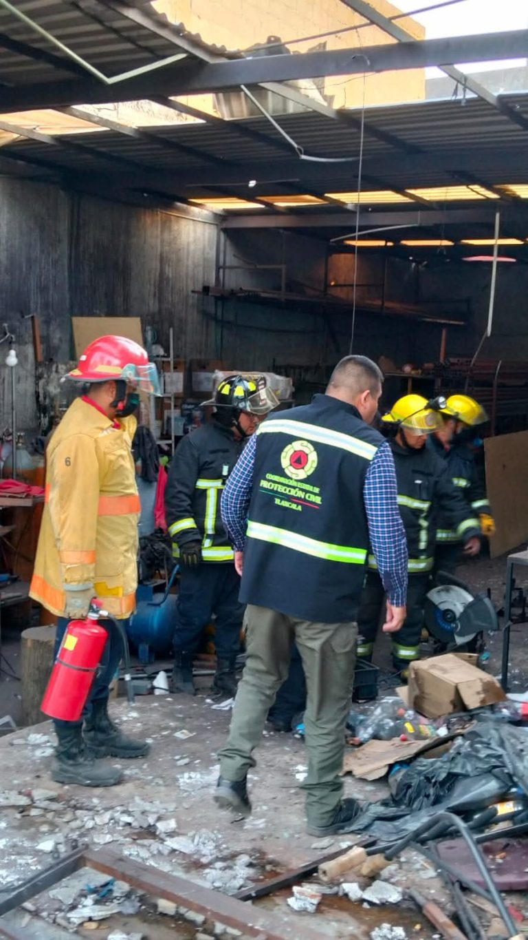 Persona de emergencia en un taller de reparación de autos, con equipo de protección, atendiendo una situación de emergencia o accidente en un ambiente industrial.