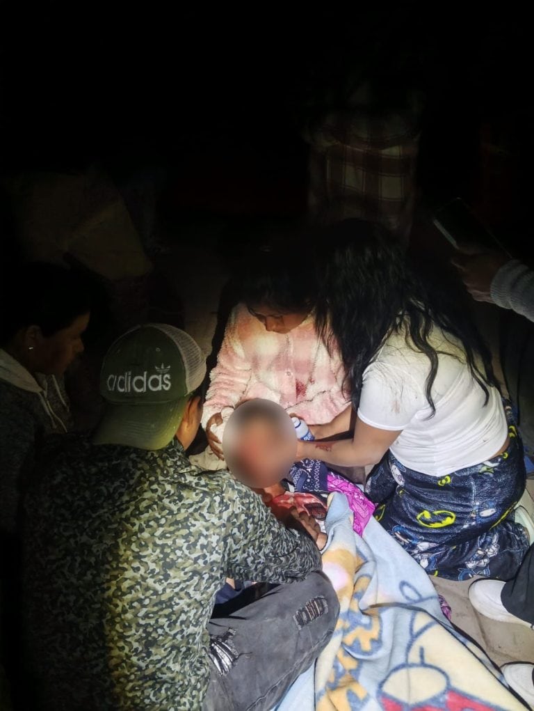 Grupo de personas atendiendo a un niño en una situación de emergencia en un entorno oscuro.