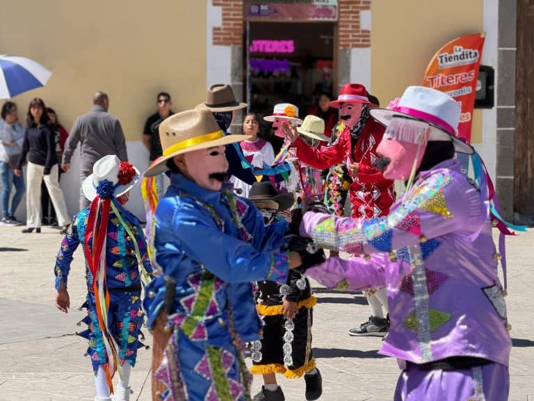 Disfraces tradicionales de la celebración de la fiesta en Tlaxcala, con personajes coloridos y máscaras en una plaza pública.