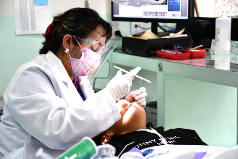 Médico realizando una prueba de vacunación en un paciente en un consultorio médico, con equipo de protección personal y ambiente clínico.