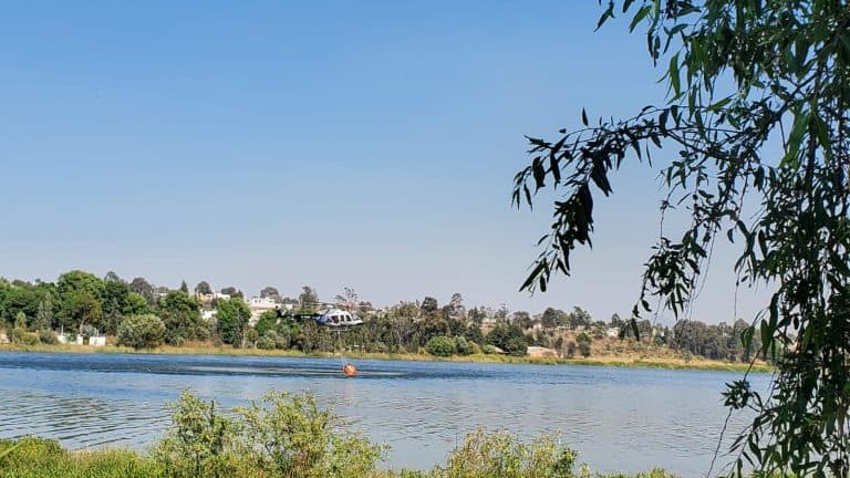 Vista panorámica de un río con vegetación y casas en el fondo, bajo un cielo despejado en Tlaxcala, México.