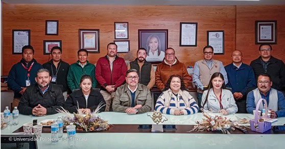 Grupo de profesionales en una reunión formal en una sala de conferencias con paredes de madera y certificados enmarcados.