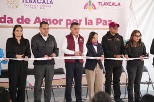 Corte de cinta en evento por la paz en Tlaxcala con autoridades y organizadores en el escenario.