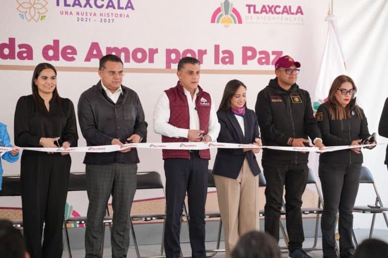 Corte de cinta en evento por la paz en Tlaxcala con autoridades y organizadores en el escenario.