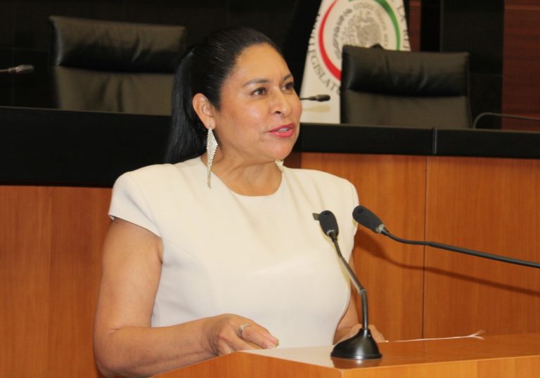 Mujer en conferencia, hablando frente a micrófono en un entorno formal y profesional.