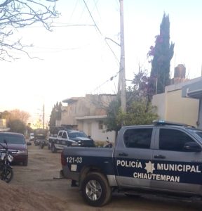 Policía municipal de Chiautempan en una calle de barrio, con varias patrullas y motocicletas, durante el día, en un entorno urbano con casas y árboles en el fondo.