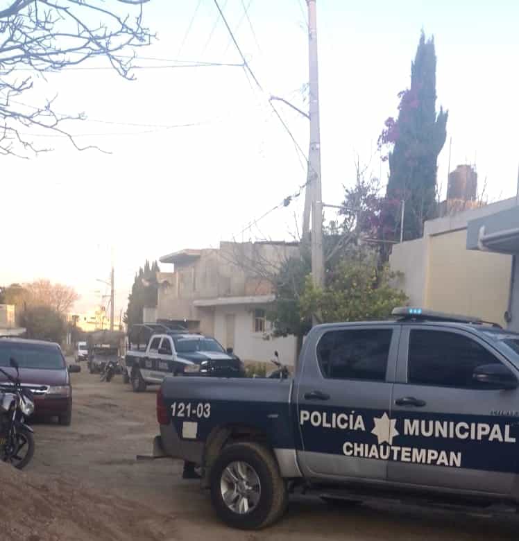 Policía municipal de Chiautempan en una calle de barrio, con varias patrullas y motocicletas, durante el día, en un entorno urbano con casas y árboles en el fondo.