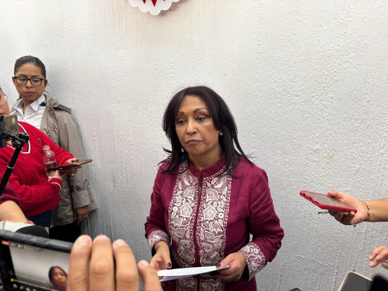 Mujer hablando con periodistas y medios de comunicación en una conferencia o evento público en interiores.