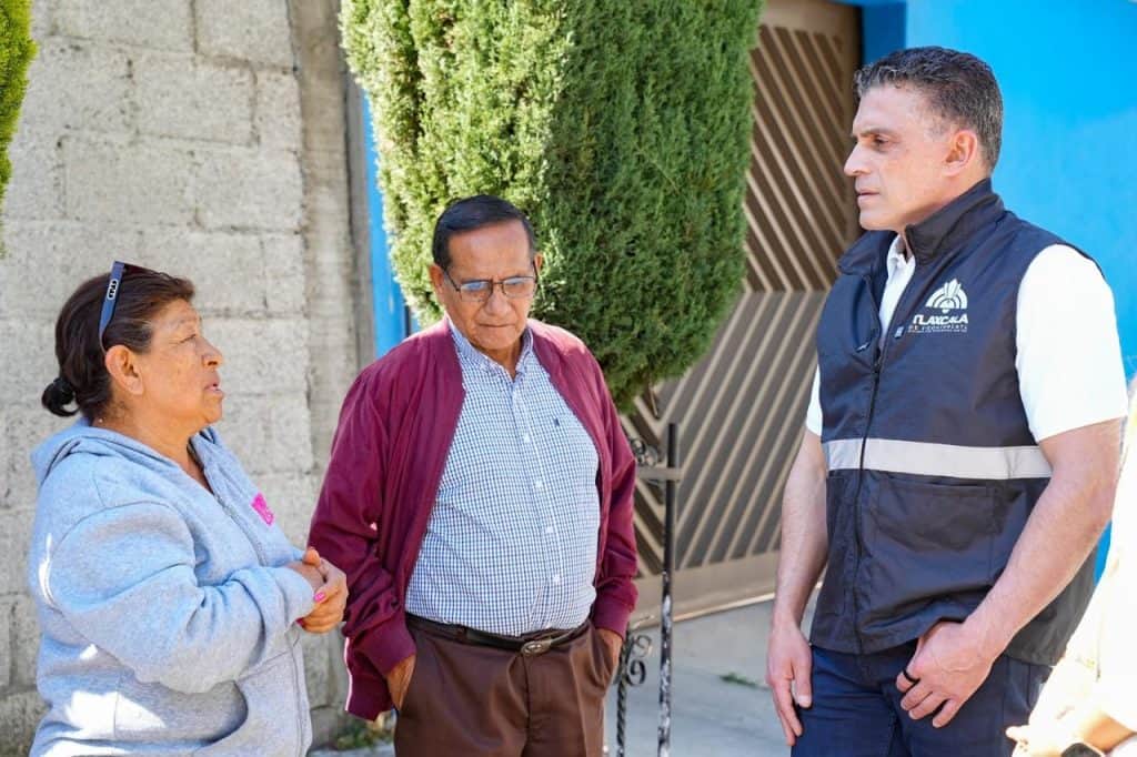 Persona de la policía conversando con dos adultos mayores en la calle en Tlaxcala, México.