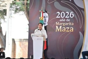 Persona hablando en un evento oficial con fondo que dice "2026 año de Margarita Maza" y bandera de México, en un entorno al aire libre.
