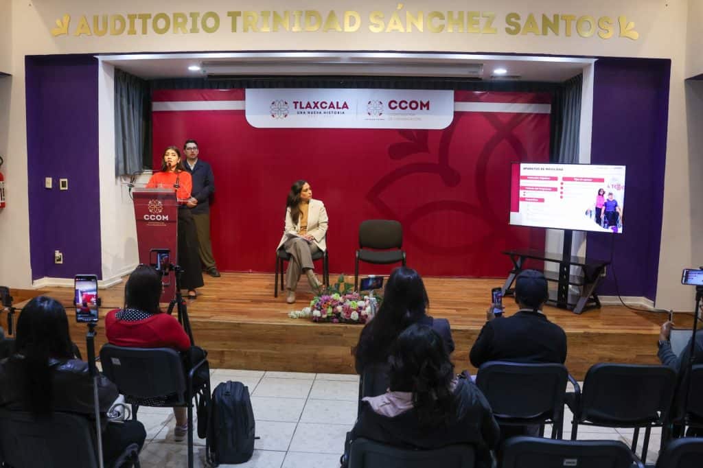 Auditorio Trinidad Sánchez Santos durante un evento con panelistas y audiencia en un espacio con señalización de Tlaxcala y CCOM en el fondo.