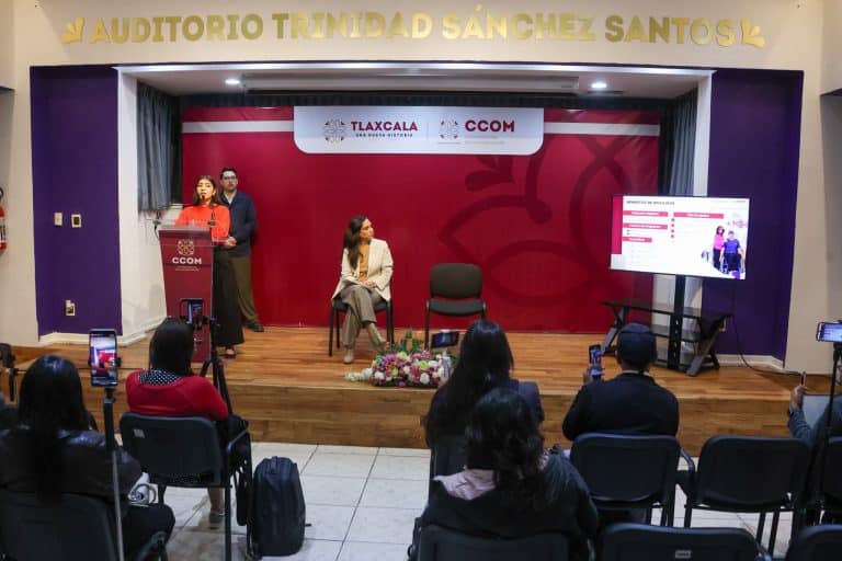 Auditorio Trinidad Sánchez Santos durante un evento con panelistas y audiencia en un espacio con señalización de Tlaxcala y CCOM en el fondo.