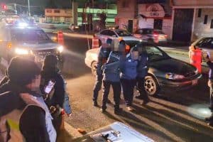 Policías en escena de un accidente vial en una calle de Tlaxcala durante la noche, con vehículos detenidos y señalización de advertencia en el lugar.