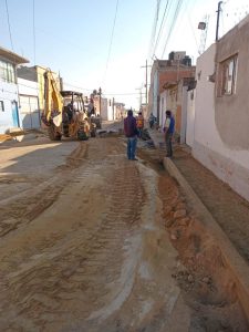Trabajos de pavimentación en calle de Tlaxcala con maquinaria y trabajadores en acción.