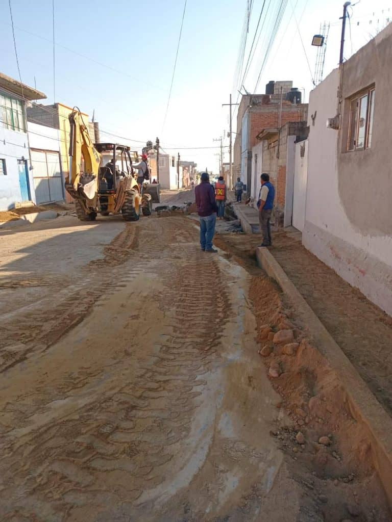Trabajos de pavimentación en calle de Tlaxcala con maquinaria y trabajadores en acción.