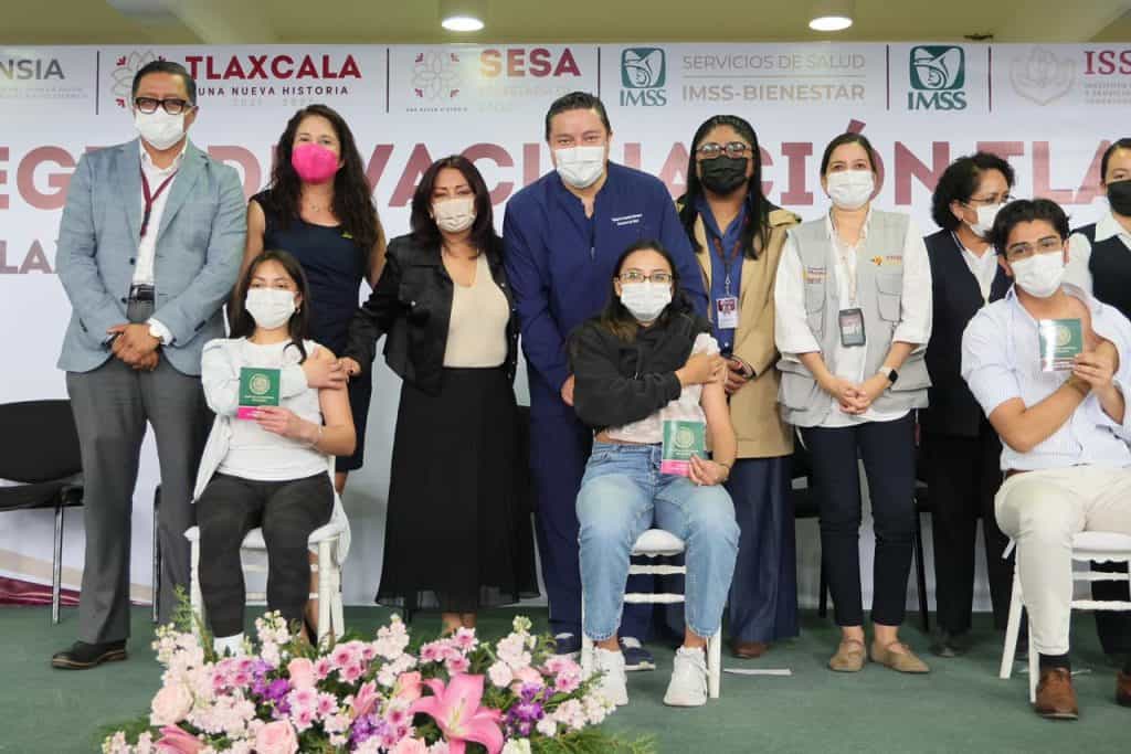 Personas en una ceremonia de reconocimiento, algunas con certificados en mano, todas usando mascarillas, en un evento formal de salud o educación en Tlaxcala, México.