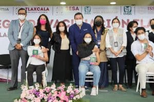 Personas en una ceremonia de reconocimiento, algunas con certificados en mano, todas usando mascarillas, en un evento formal de salud o educación en Tlaxcala, México.
