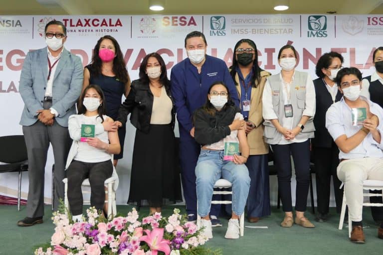Personas en una ceremonia de reconocimiento, algunas con certificados en mano, todas usando mascarillas, en un evento formal de salud o educación en Tlaxcala, México.